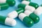 Closeup of green and white pills on a blue background. Heap of pills - medical background