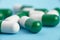 Closeup of green and white pills on a blue background. Heap of pills - medical background