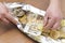 Closeup of grilled carp fish in foil with lemon,onion.Male hands holding spatula with slices of lemon