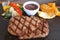 Closeup Grilled Ribeye Steak with Sauteed Vegetables and Red Wine Sauce Served on Hot Stone Plate