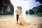 Closeup groom blonde bride in fluffy stand join hands on beach