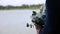 Closeup of groom and bride hold bouquet against background of lake. Copy space