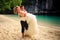 closeup groom carries in arms blonde bride in fluffy on beach