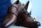 Closeup of groom's brown shoes and engraved gold wedding rings on it