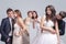 Closeup of Group of Five Loving Caucasian People Standing in Pairs of Two in Wedding Clothing. Against Gray Background