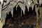 Closeup of a group of small stalactites hanging from the ceiling of a cave