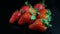 Closeup group of whole ripe fresh juicy red strawberries served on black background