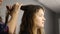 Closeup hairdresser makes hairstyle for young woman in beauty salon