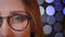 Closeup half face portrait of young pretty caucasian girl in glasses looking at camera and smiling happily with bokeh