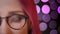 Closeup half face portrait of young pretty caucasian girl with red dyed hair in glasses looking at camera and smiling