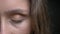 Closeup half-face shoot of young pretty caucasian brunette female face with brown eye being closed in front of the