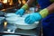 Closeup of hand in blue gloves, diligently cleaning dishes after daily meals
