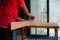 Closeup hand of carpenter holds electrical tool scrubbing the surface of wood