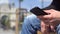 Closeup of the hand of a caucasian young male with a phone. A man types a message on the city street