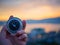 Closeup hand holding compass with mountain and sunset sky