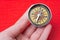 Closeup of a hand holding a compass on a red surface - navigation concept