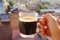 Closeup Hand Holding a Cup of Hot Coffee Against Blurry City View