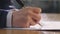 Closeup of hand holding pen and signing on document
