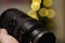 Closeup of a hand holding a specialized professional camera lens with bright yellow bokeh behind it