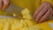 Closeup of hand with knife cutting fresh vegetable. Woman cutting potatoes on a white cutting board closeup.