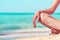 Closeup hand and leg of woman sit on sand beach at seaside. Happy young Asian woman relax and enjoy holiday at tropical paradise
