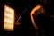 Closeup hand of a man using halogen heater to keep warm in winter isolated in black background