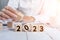 Closeup of the hand placing wooden cubes on the table. 2023 new year plans concept.