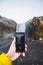Closeup of a hand taking a video of the Skogafoss waterfall with a phone in Iceland