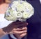 Closeup hands of bride and groom holding wedding white bouquet