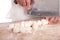 Closeup of hands of chef using kitchen knife to cut noodles on cutting board into small dough