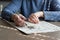 Closeup of hands of elderly woman, sitting at table in her home, solving crossword puzzle. Cognitive rehabilitation therapy for