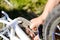 Closeup on hands of father fixing mechanism of the bicycle, green background outside