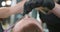 Closeup hands of female barber, who cuts eyebrows of young bearded man with pink scissors and comb