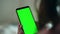 Closeup hands holding chromakey smartphone in evening. Unknown woman reading