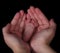 Closeup of hands holding newborn foot on black