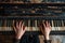 closeup of hands on the keys of an very old shabby piano