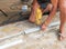 Closeup hands of laborer holding electric drill working drilling aluminum lumber at construction site