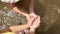 Closeup hands of little girl scoops up water to flowing in to sister hand in river. Concept of childhood happiness.