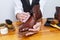 Closeup of Hands of Male Shoes Cleaner with Cleaning Brushes For Tan Derby Leather Boots While Working in Workshop