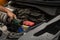 Closeup, The hands of a male technician are using a tool to replace the car battery, parked at home. Black car, the battery