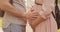 Closeup hands of man touching pregnant belly of his woman in park.