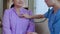 Closeup hands nurse or caregiver sitting on sofa holding stethoscope listen heartbeat with senior woman.