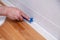 Closeup hands of professional plumber worker applying white sealant, joint compound, caulk to joint of wooden table top