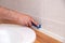 Closeup hands of professional plumber worker applying white sealant, joint compound, caulk to joint of wooden table top