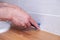 Closeup hands of professional plumber worker applying white sealant, joint compound, caulk to joint of wooden table top