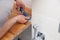 Closeup hands of professional plumber worker applying white sealant, joint compound, caulk to joint of wooden table top, beige