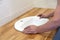 Closeup of hands of professional plumber worker installs white oval ceramic sink on wooden table top in bathroom with beige tile