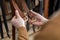 Closeup hands of professional tanner choosing belt buckle on wooden table at leather workshop