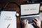 Closeup of hands using computer laptop with empty screen with blank paper