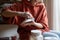 Closeup hands woman ceramist with saucer and hard sponge for buffing dishes after pottery kiln